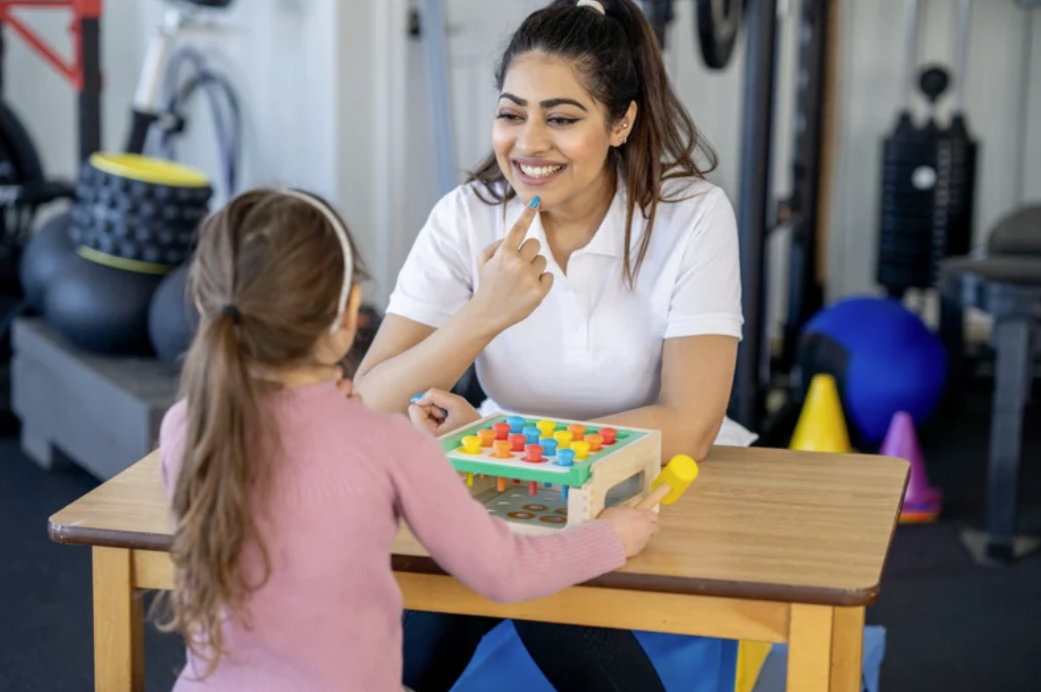 Therapist working with child using colorful pegs during OT session