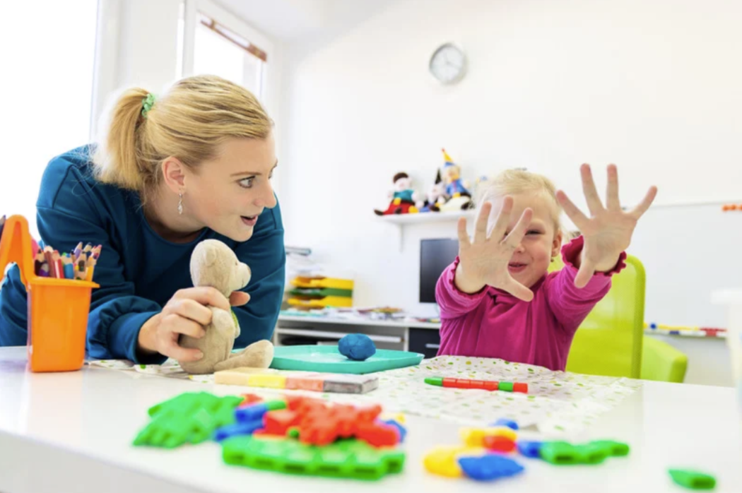 Child and therapist working with play doh during OT session